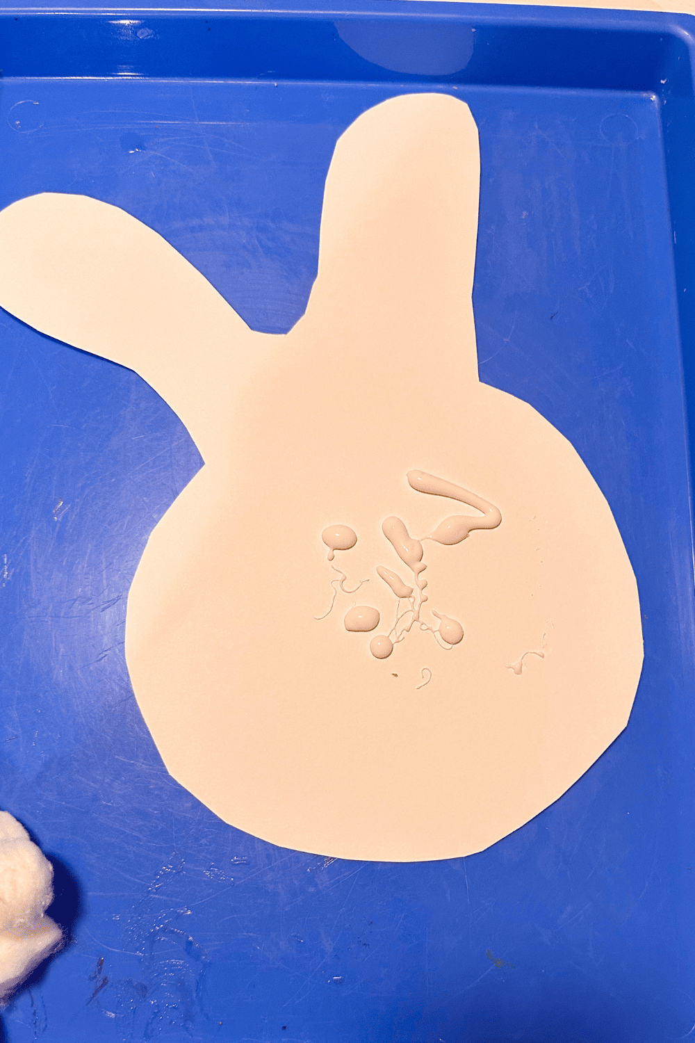 paper cut into a bunny shape with glue in the center