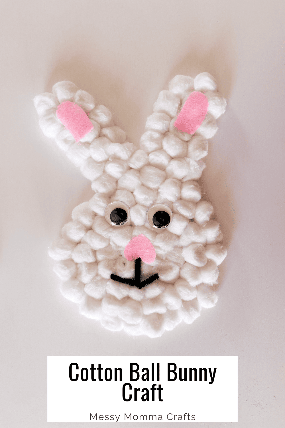Cotton ball bunny with pink ears, googly eyes, and a black mouth.