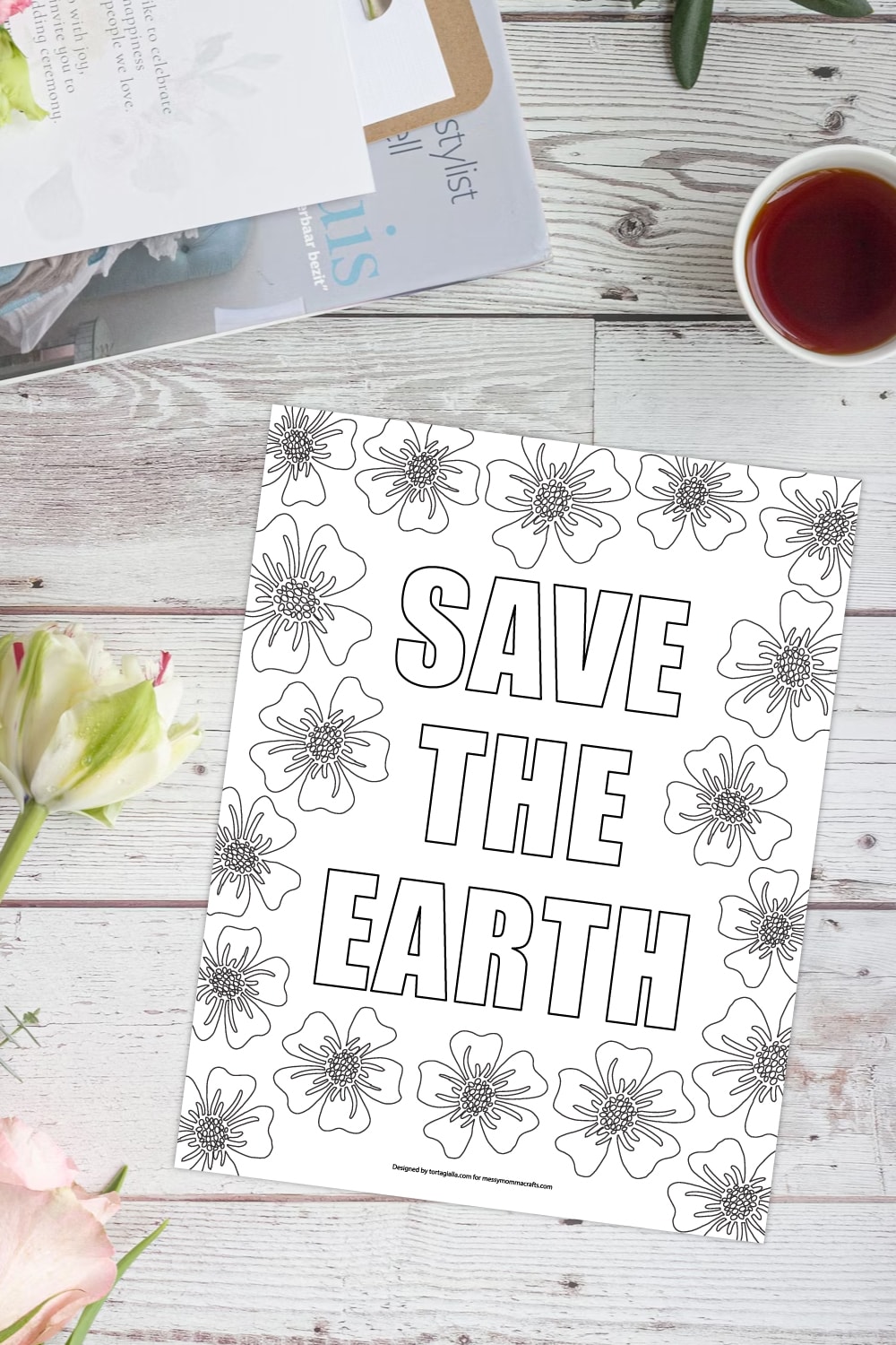 Preview of save the earth coloring page illustration on white wooden plank background with view of cropped laptop on top left, cup of coffee on top right and flowers on the left side border. 