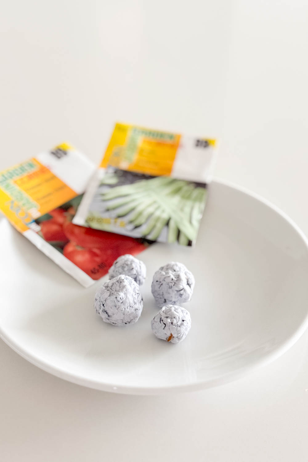 Seed bombs sitting on a white plate with additional seed packets in the background