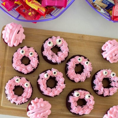 Pink monster donuts made from chocolate doughnuts, pink frosting, and googly eyes.